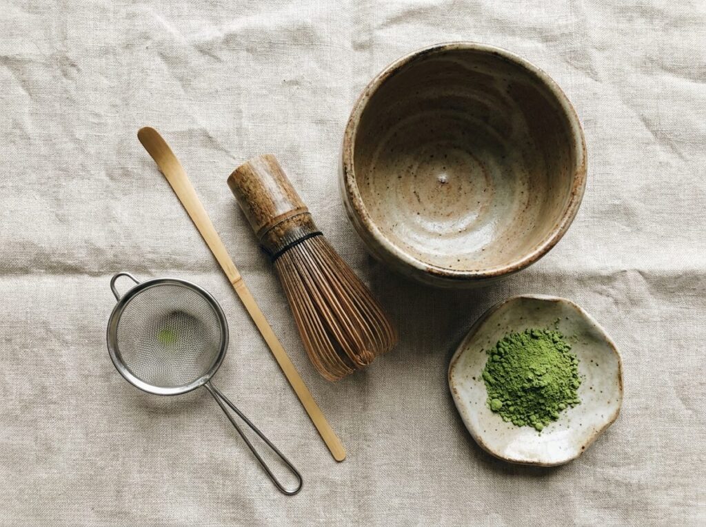 Matériel pour préparer le matcha vu du dessus : bol chawan, fouet chasen, cuillère chashaku, tamis et poudre de thé vert