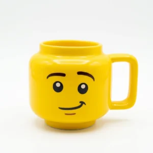 3be9b0fd-863a-410c-808d-6cca695e6248.webp Mug jaune en céramique en forme de tête de personnage souriant avec une anse