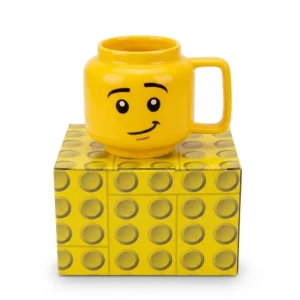 c7583d50-070a-4902-93c2-b6c7b51ac995.webp Mug jaune en forme de tête de personnage posé sur sa boîte décorée